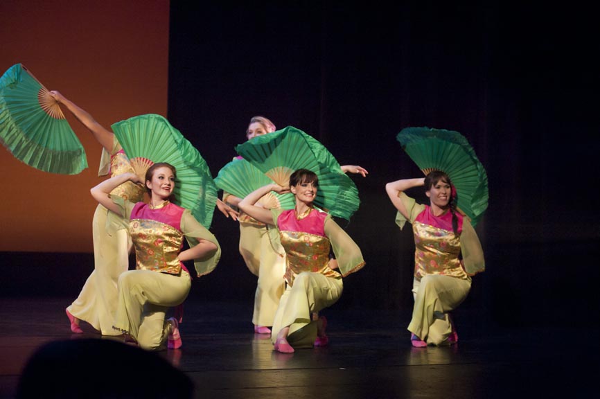 Need descriptions for each of the images       Intermediate Ballet Technique class          dancer flying off back of another dancer          duet using chair as a prop          confetti in air, dancers showing exuberance          dancers in Chinese folk fan dance          dancers making a group shape that is reaching for light          dancers holding umbrellas upward, with delight          duet dancing with sofa          duet in soft blue light, making a pose          dancers on stage in blue light in a lunge          dancers in circle surrounding a soloist          duet dancing in soft blue light in a curved shaped pose          duet in a lift